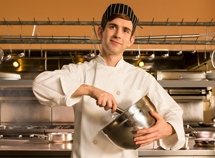 Student chef in grey uniform cooks for Mission Bistro.