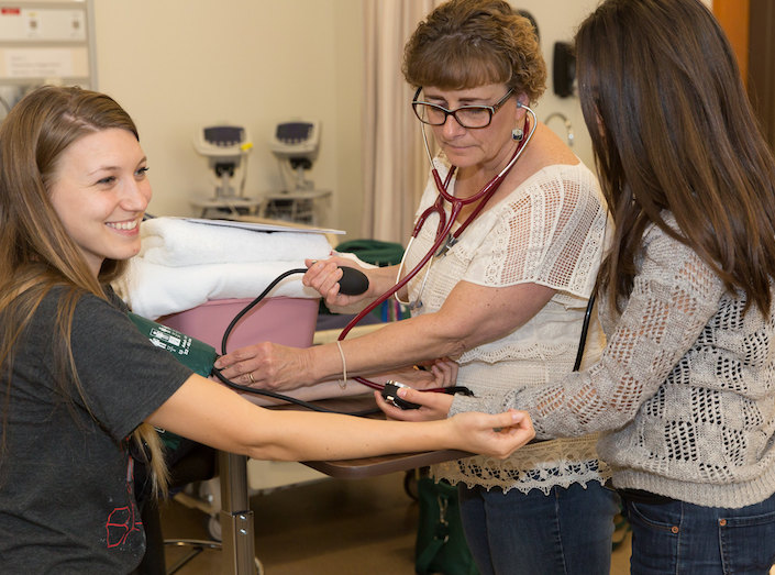 An LVN instructor demonstrates a concept to young LVN female nursing students.