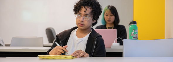 Student writing at desk