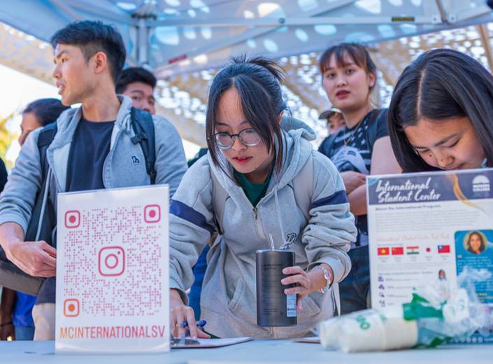 Strudents sign up at an information table for an IIS event.